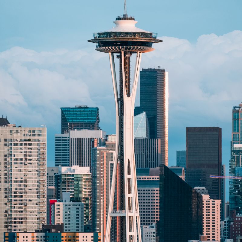 The image features a skyline including the Space Needle, a prominent observation tower in Seattle, with various modern buildings in the background.